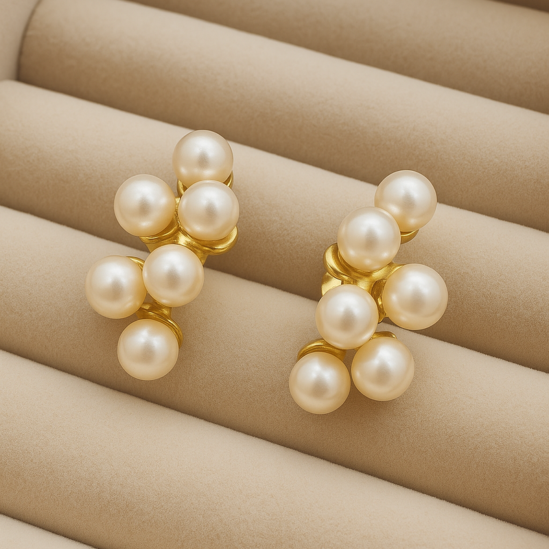 Pair of pearl earrings on a beige cushion